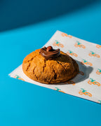 Baked good with chocolate topping on a patterned paper against a blue background
