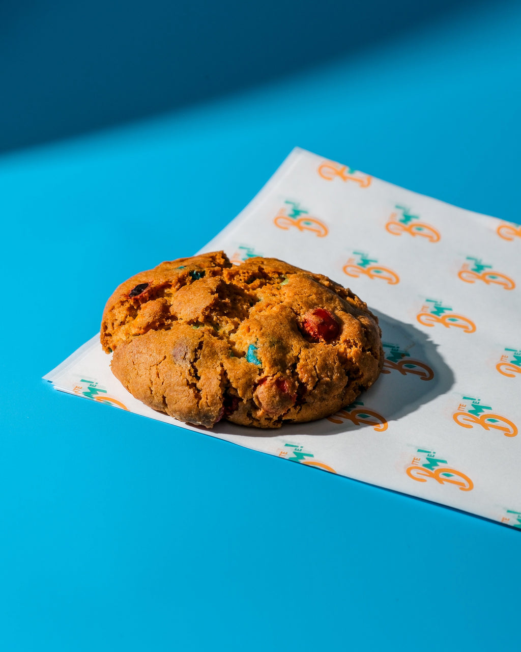 M&M Cookie on a blue background with a patterned paper