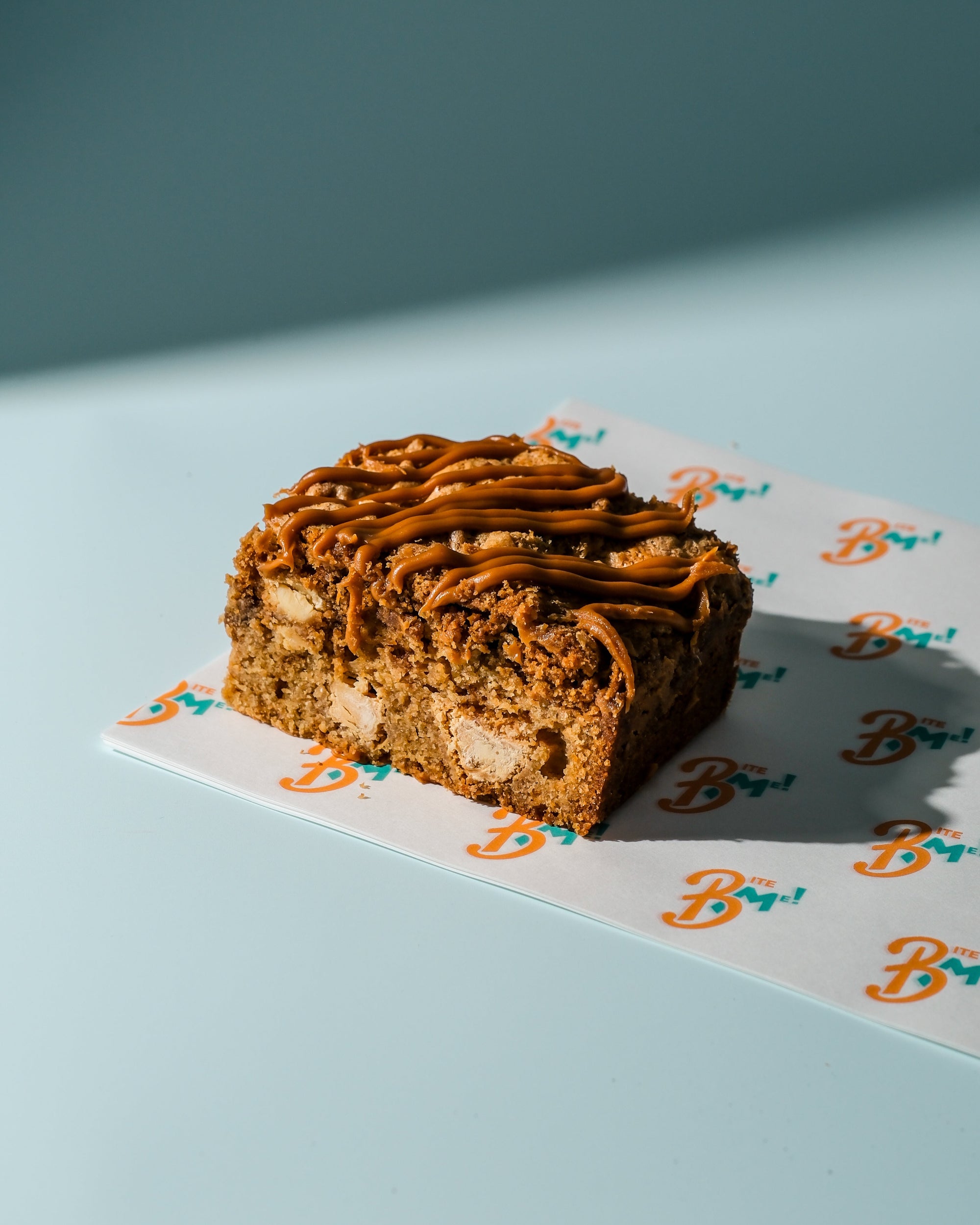 Biscoff blondie with biscoff drizzle on a decorative paper with 'B' logo
