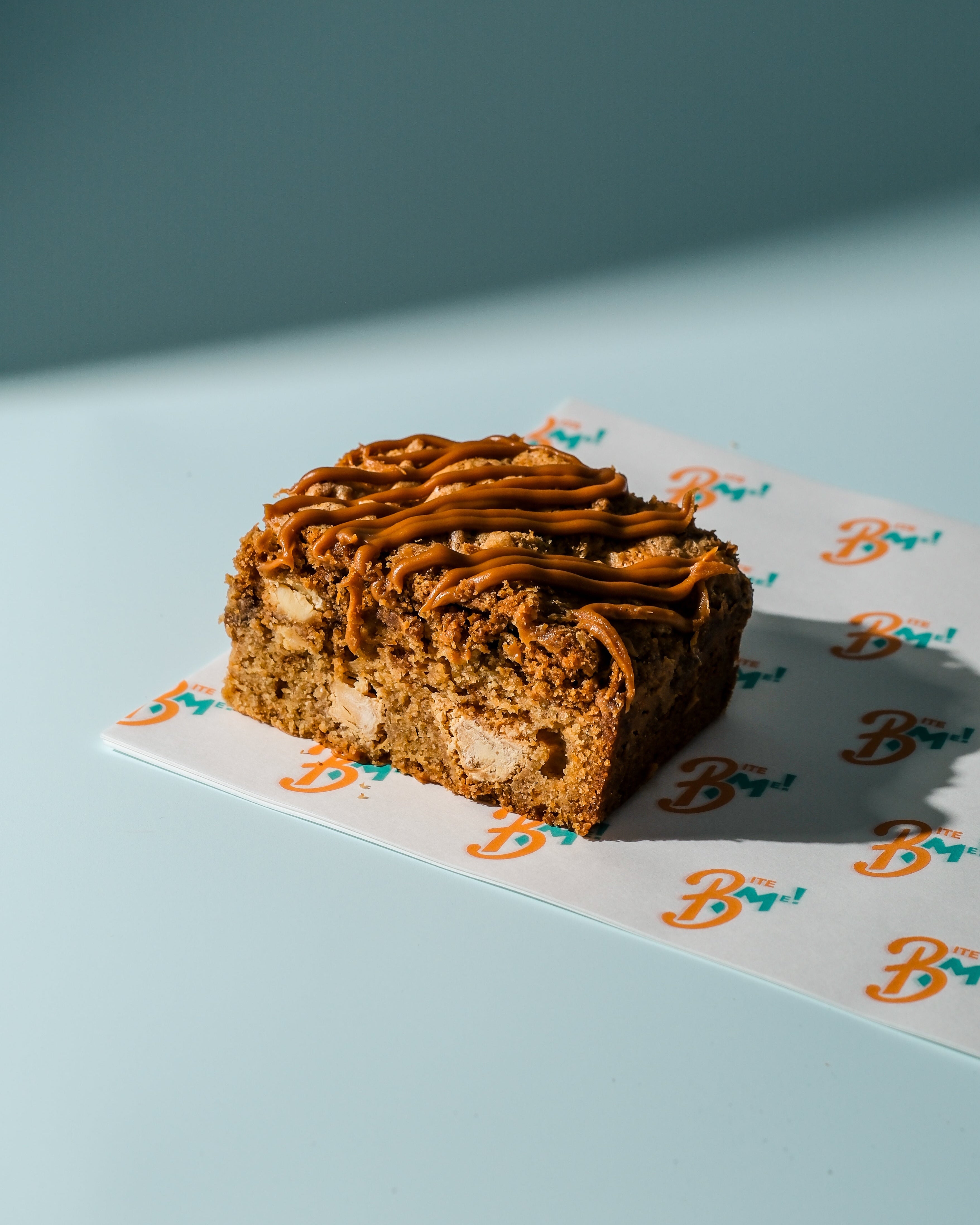 Biscoff blondie with biscoff drizzle on a decorative paper with 'B' logo