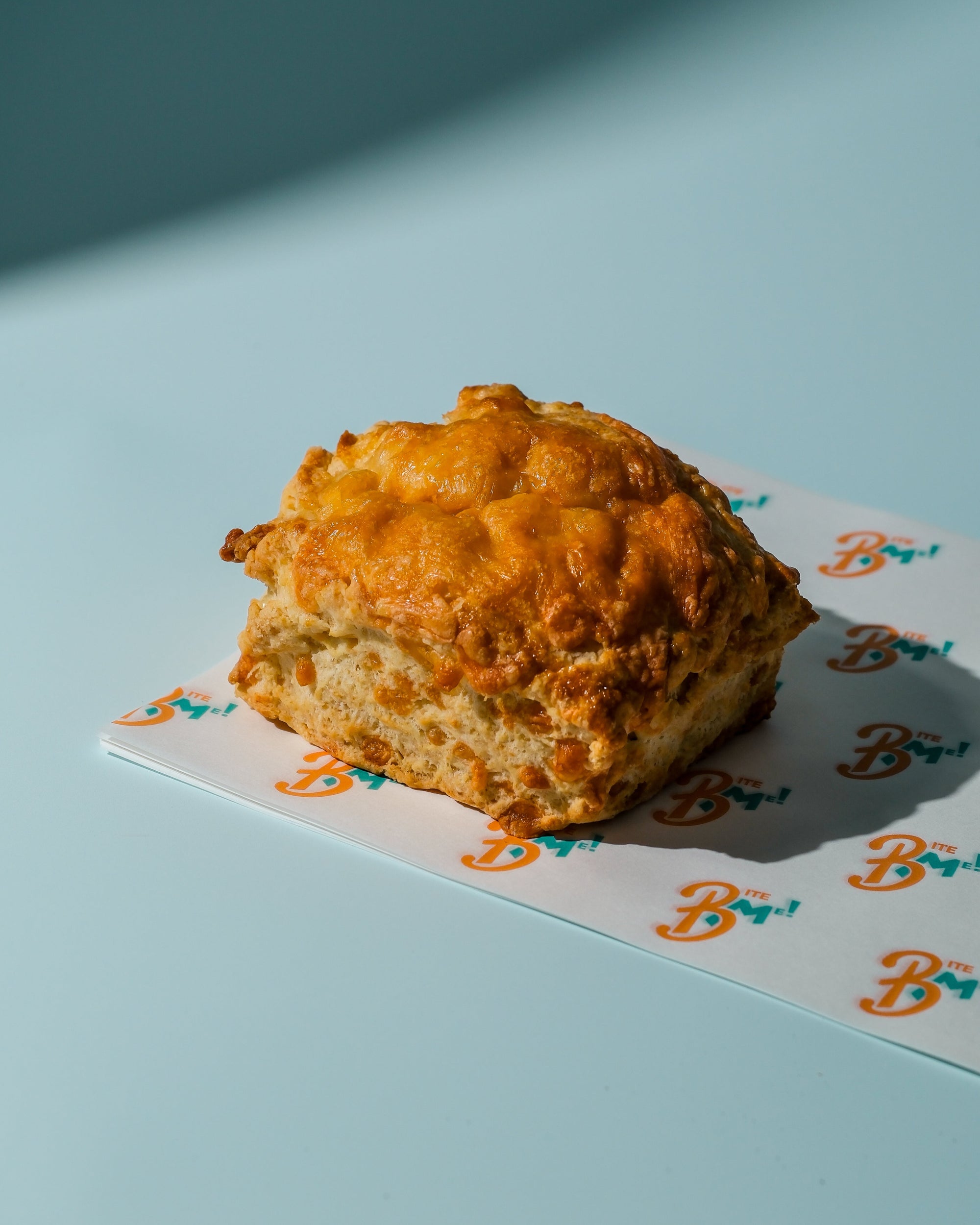 Cheese scone on a blue background with a brand logo